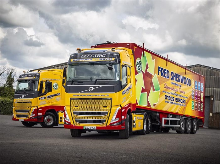 Two Volvo FH Electric trucks with Fred Sherwood Transport livery sit in a parking lot.
