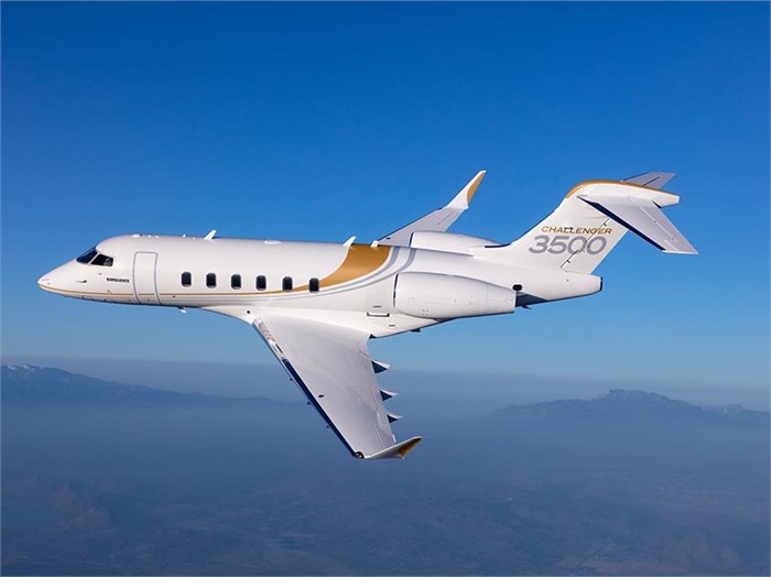 A white, 10-seat Bombardier Challenger 3500 business shown flying with mountains in the lower background.