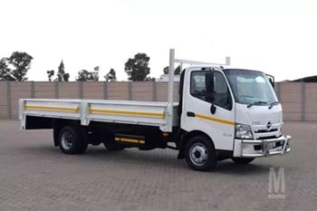 A 2023 Hino 300 916 flatbed truck parked on a lot.