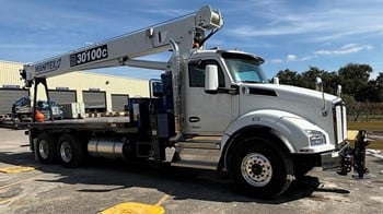 A 2025 Manitex 30100C boom truck crane parked on a lot.