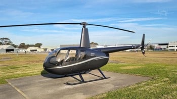 A 2026 Robinson R44 Raven II piston helicopter on a landing pad.