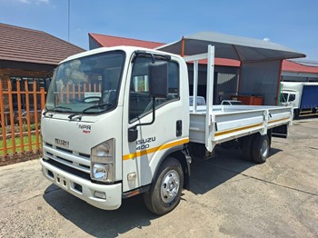 A 2021 Isuzu NPR dropside flatbed truck parked outdoors.