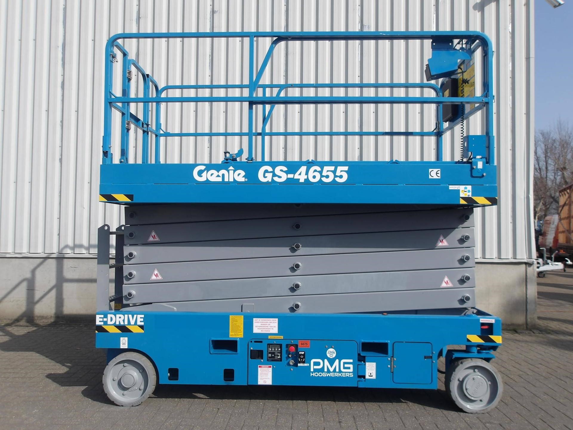 Blue 2022 Genie GS4655 slab scissor lift parked outdoors with a white shed in the background.