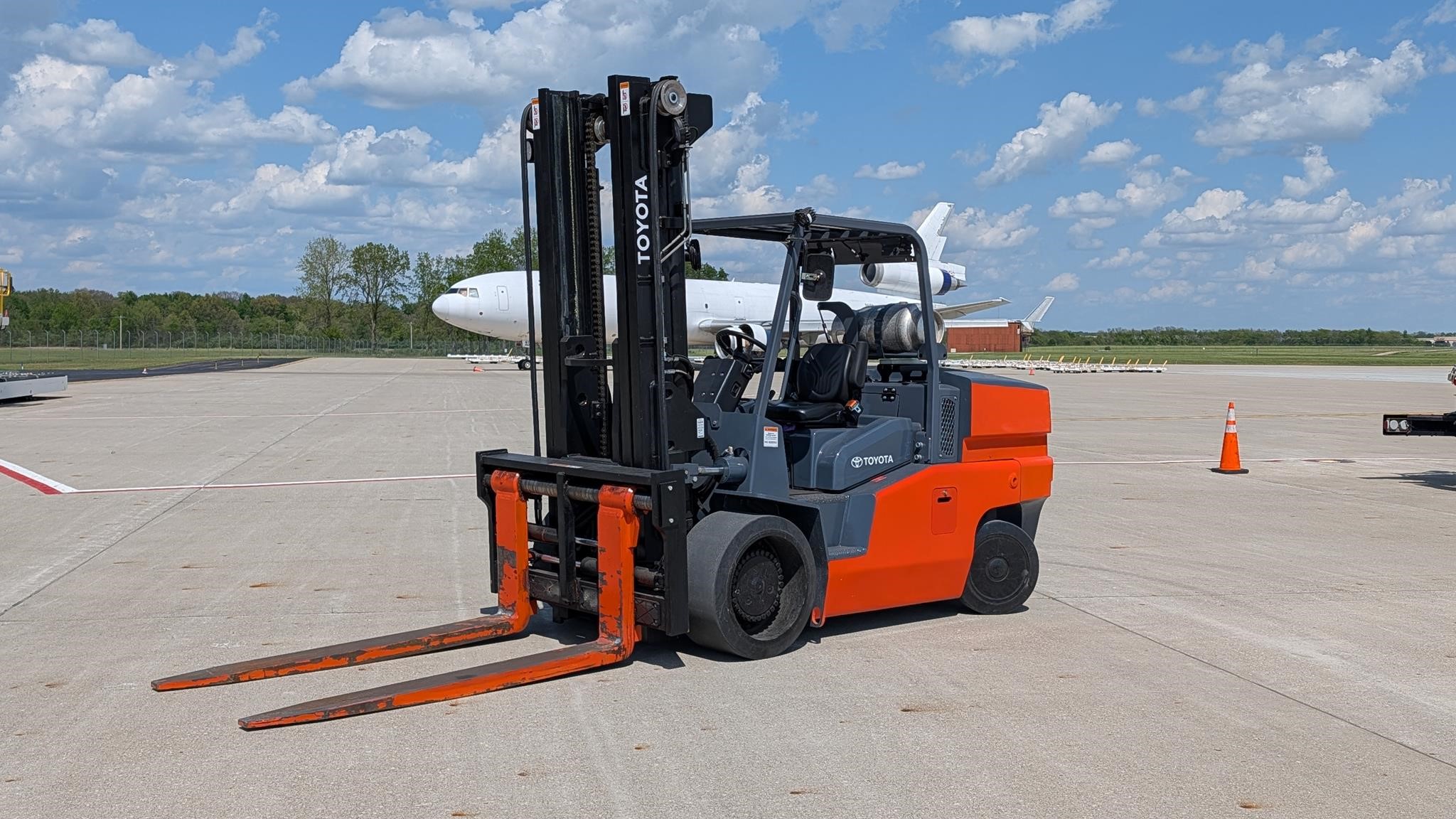 2024 Toyota THDC2200-24 solid-tyre forklift parked outdoors on a tarmac with an airplane in the background.