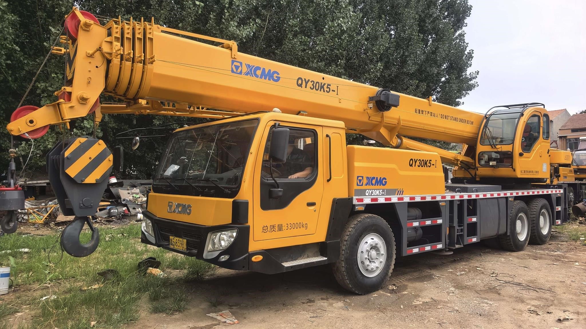 A 2023 XCMG QY30K5-I telescopic boom truck crane sits on a dirt lot.