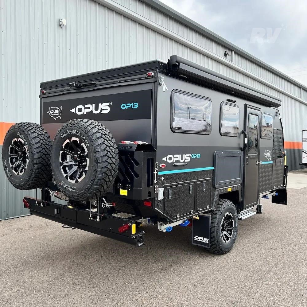 A 2026 Opus Off-Road OP13 travel trailer parked outdoors by a building.