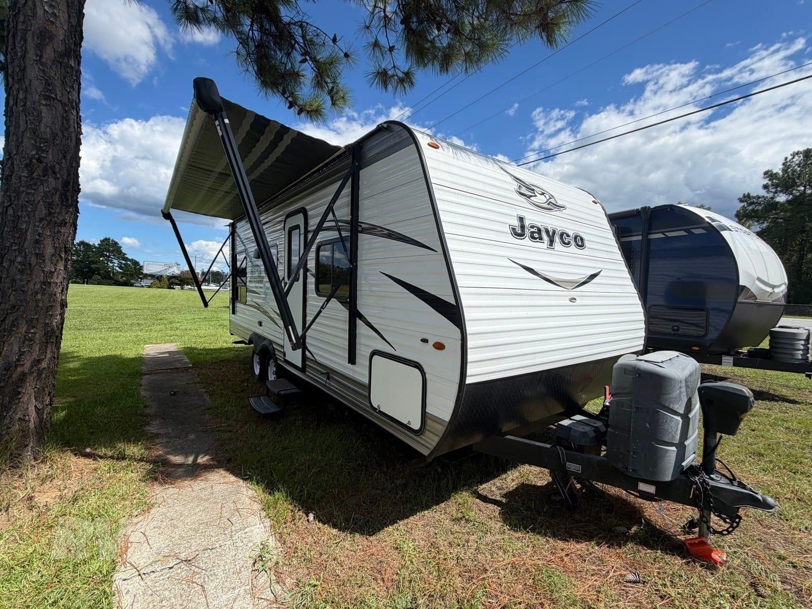 A 2018 Jayco Jay Flight 212QB travel trailer parked outdoors in a grassy area.