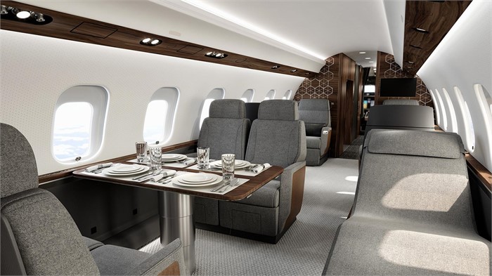 The interior of a Bombardier Global 6500 business jet with 4-place dining table, Nuage seats, and a rear-facing Nuage chaise.