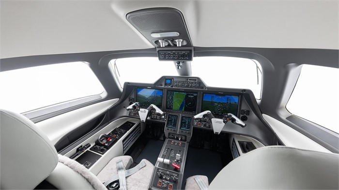 The cockpit of an Embraer Phenom 100EX light jet with three 14.1-inch color displays and dual flight controls.