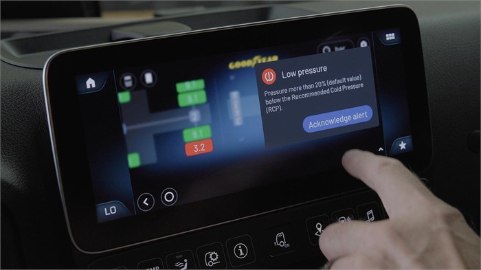 A truck driver acknowledges a low-pressure warning on his truck’s touchscreen display using the Goodyear DriverHub app.