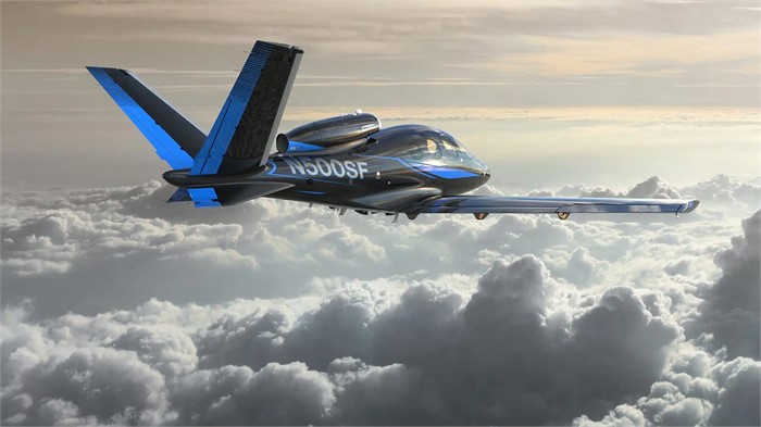 A black-and-blue Cirrus Aircraft Special Edition Vision Jet flies above white clouds.