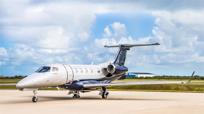 An Embraer Phenom 300E business jet sitting on a paved tarmac.