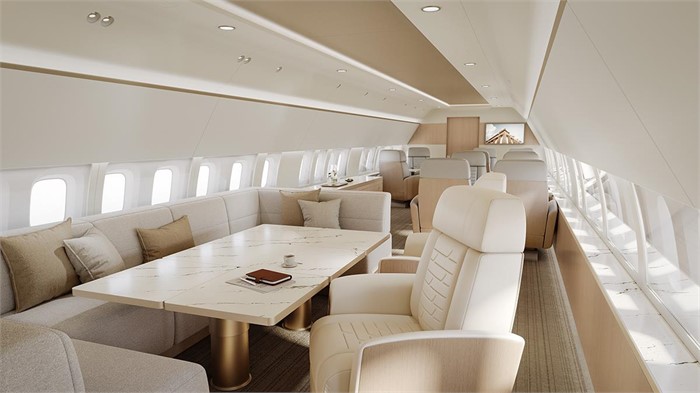 The interior of a Boeing Business Jets 737-7 Max business jet with conference table, club seats, and couch shown. 