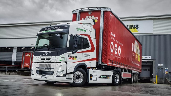 A Volvo FM Electric truck belonging to Hawkins Logistics sits parked behind the company’s building.