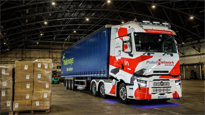 A customised Renault Trucks T520 High sits in a warehouse next to shrink-wrapped pallets.