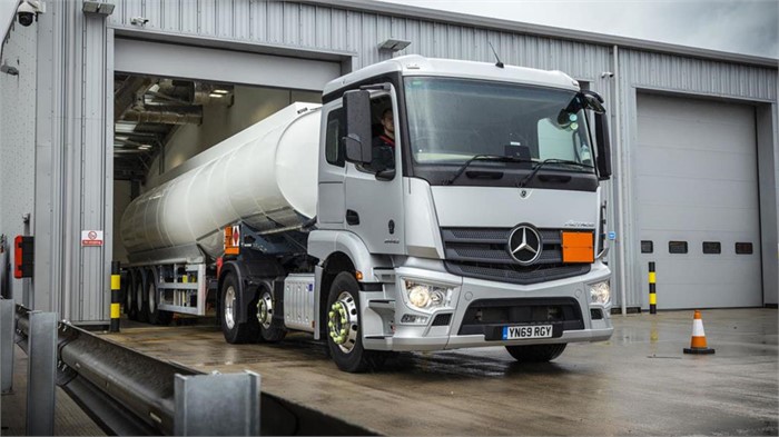 A Mercedes-Benz Actros tractor unit pulls out of a service bay pulling a hazardous materials tank semitrailer.