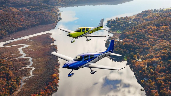 Two Cirrus Aircraft SR Series G7 piston-single airplanes, one yellow and one blue, flying over a river.