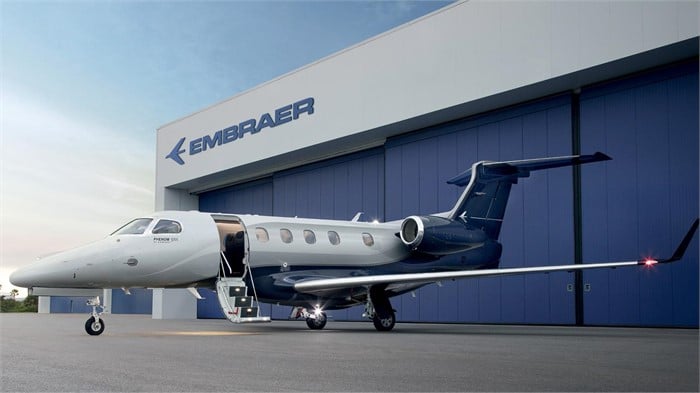 An Embraer Phenom 300E jet sits on a tarmac outside an Embraer facility.