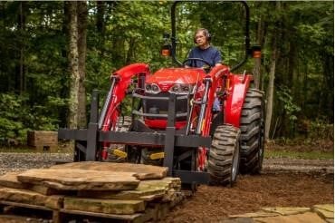 a picture of a person driving a tractor hauling lumber