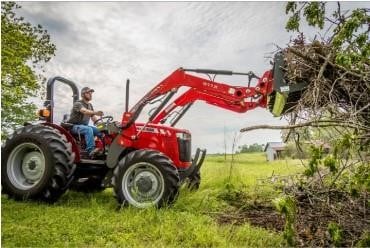 a person driving a red tractor and lifting a load of brush with the front bucket