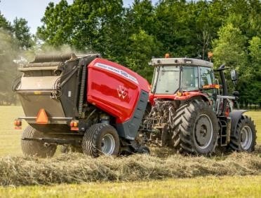 a red baler being pulled by a red tractor working in the field