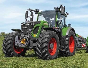 a picture of a green tractor with red rim wheels sitting in a field